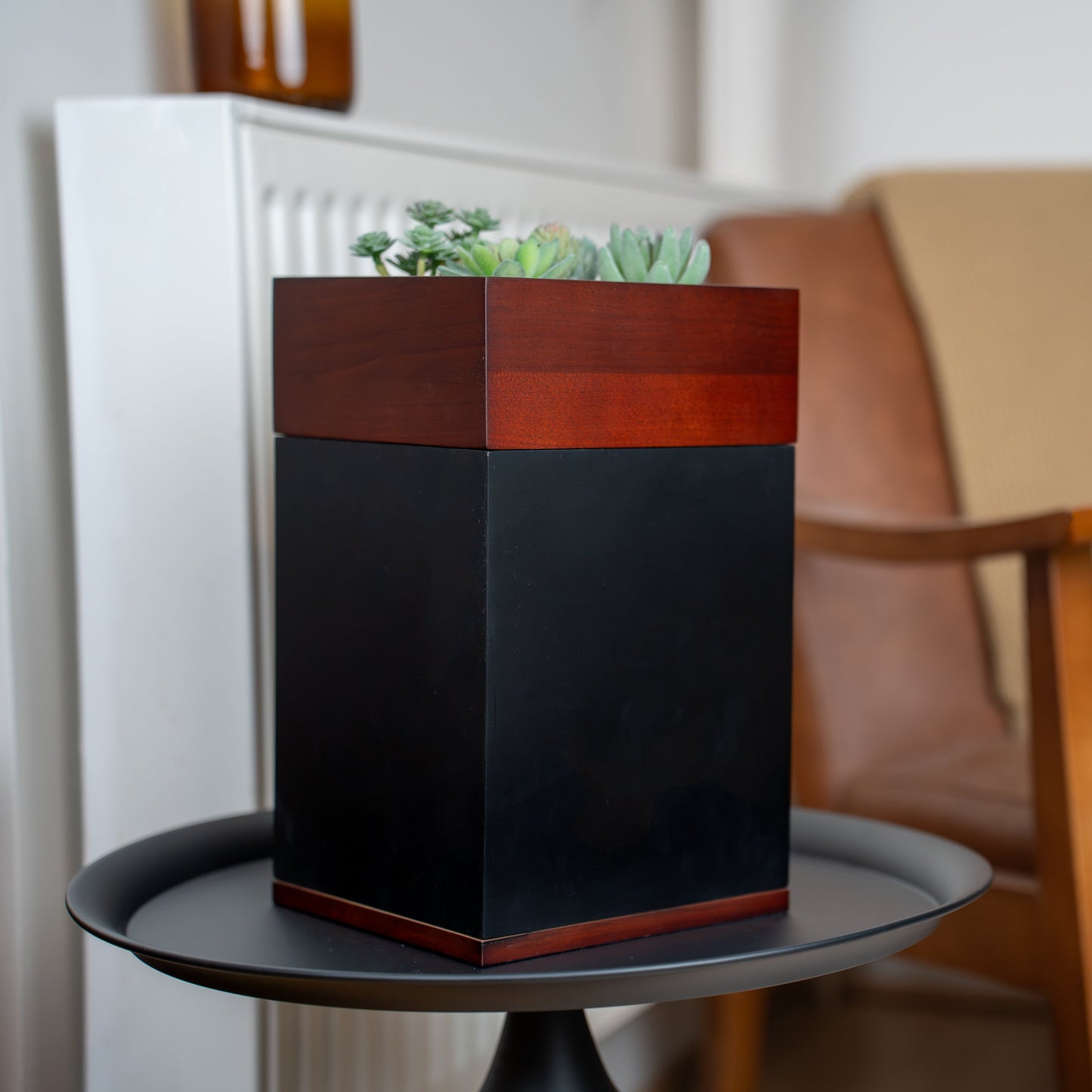 Decorative planter with plants on a small round table.